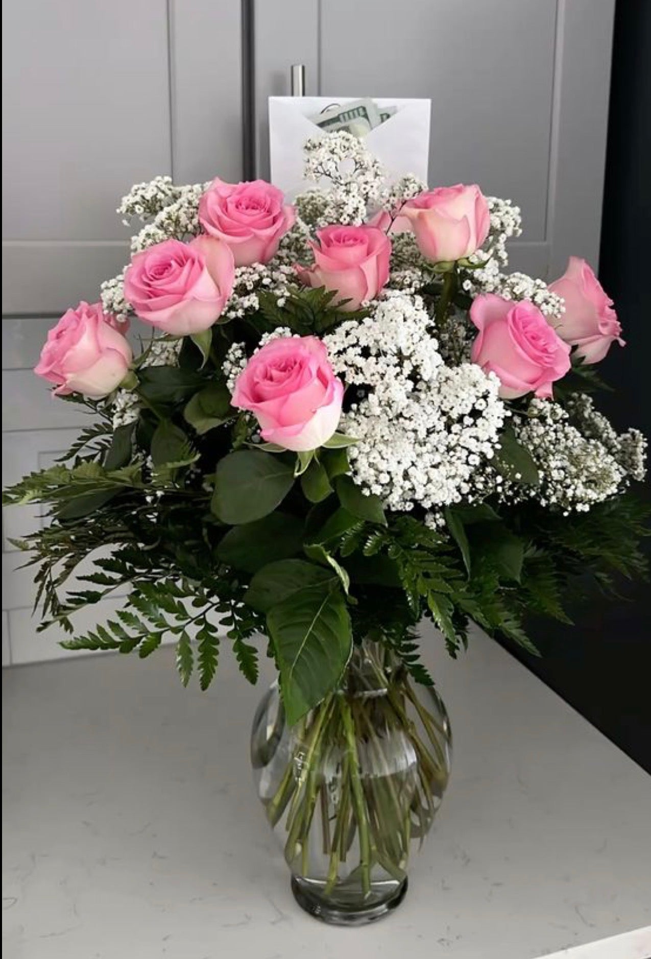 Arreglo floral en Vase de cristal , 12 rosas rosadas con baby breath y con hojas verdes leatherleaf