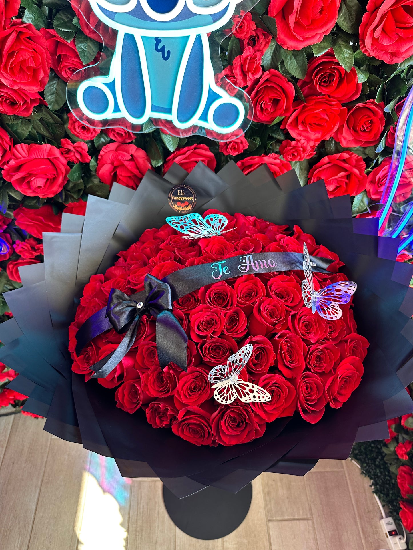 Ramo de 75 rosas rojas con papel negro alrededor y un listón personalizado con la frase (Te Amo)