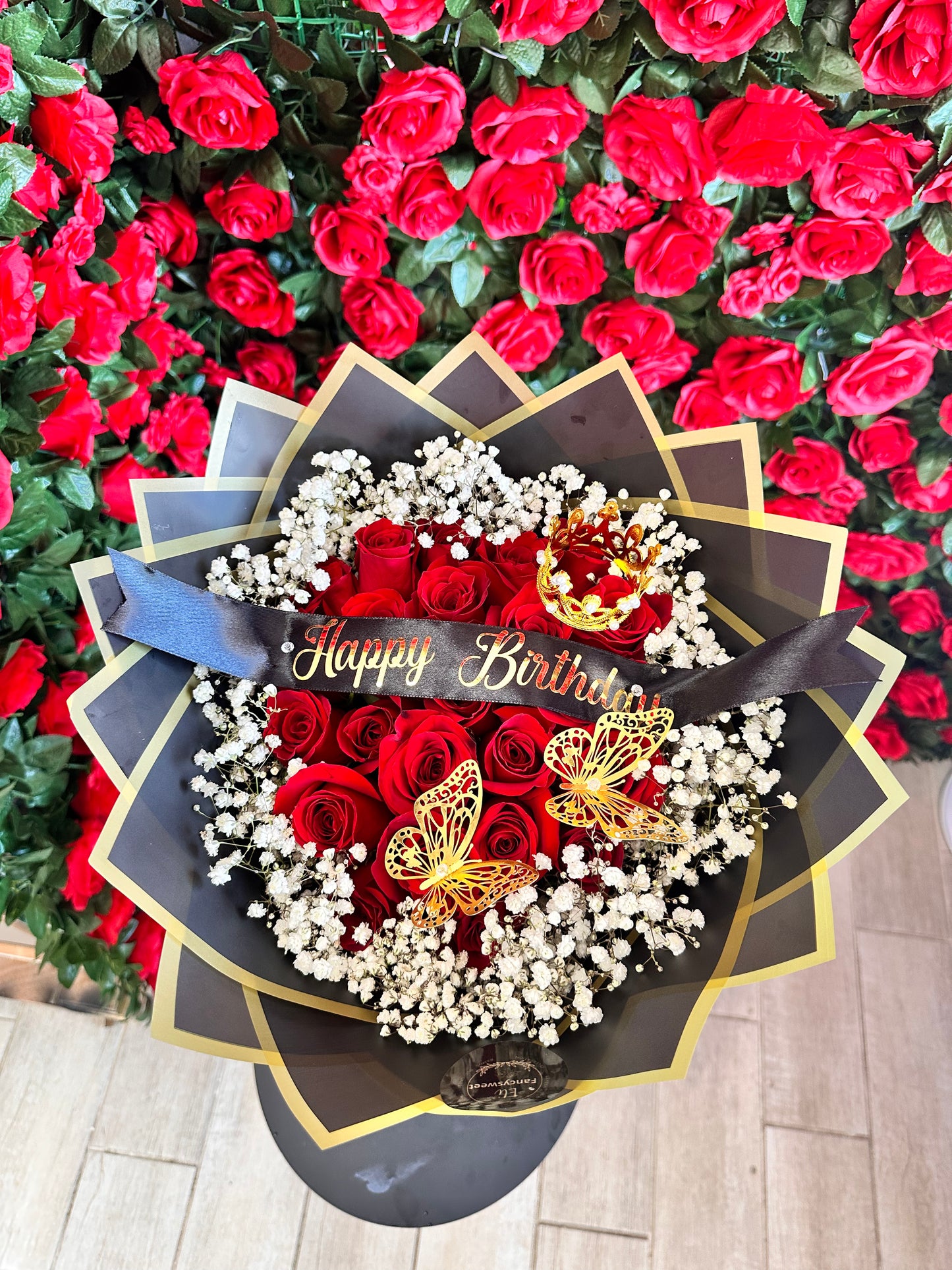 Ramo de 24 rosas rojas con baby breath ( nube) alrededor con papel negro y dorado en la orilla , con una frase personalizada en medio (Happy Birthday)