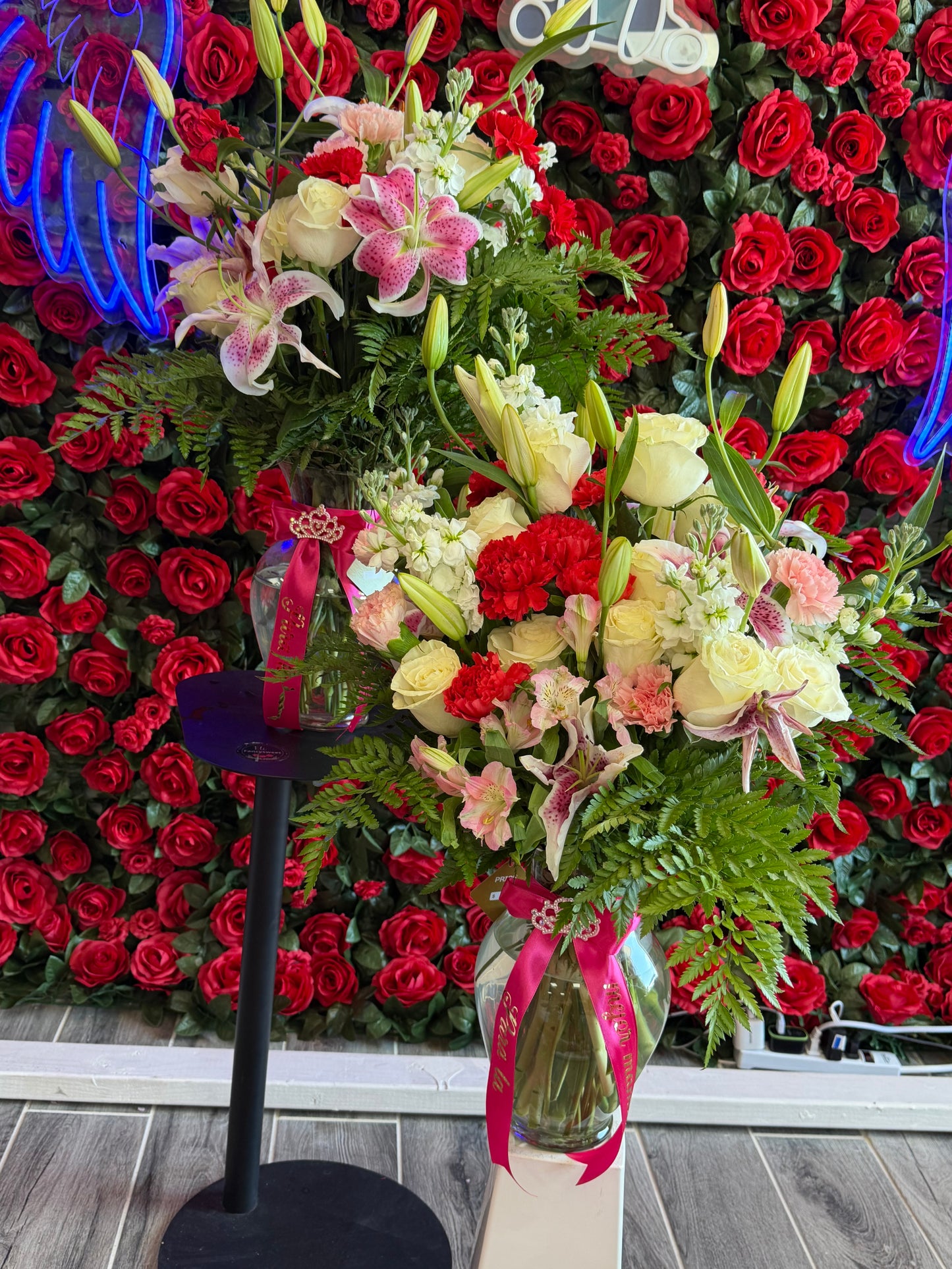 Un arreglo floral en florero de cristal ,hojas verdes ,18 rosas blancas, 7 claveles rojas ,6 claveles rosados ,Lilis , white o Pink stock moño rojo de decoración