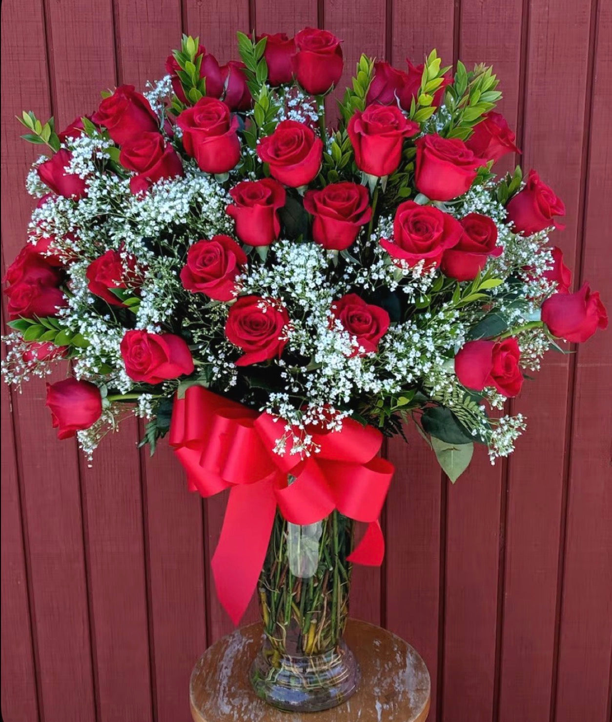 Arreglo floral en vase de cristal con 36 rosas rojas con baby breath , y hojas verdes