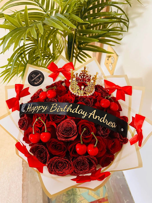 Ramo de 36 rosas rojas con mitad rellenado de brillo, una corona mediana dorado, con 8 cerezas falsas , 6 moños rojas alrededor con papel blanca y dorado en la orilla y un listón personalizado en medio