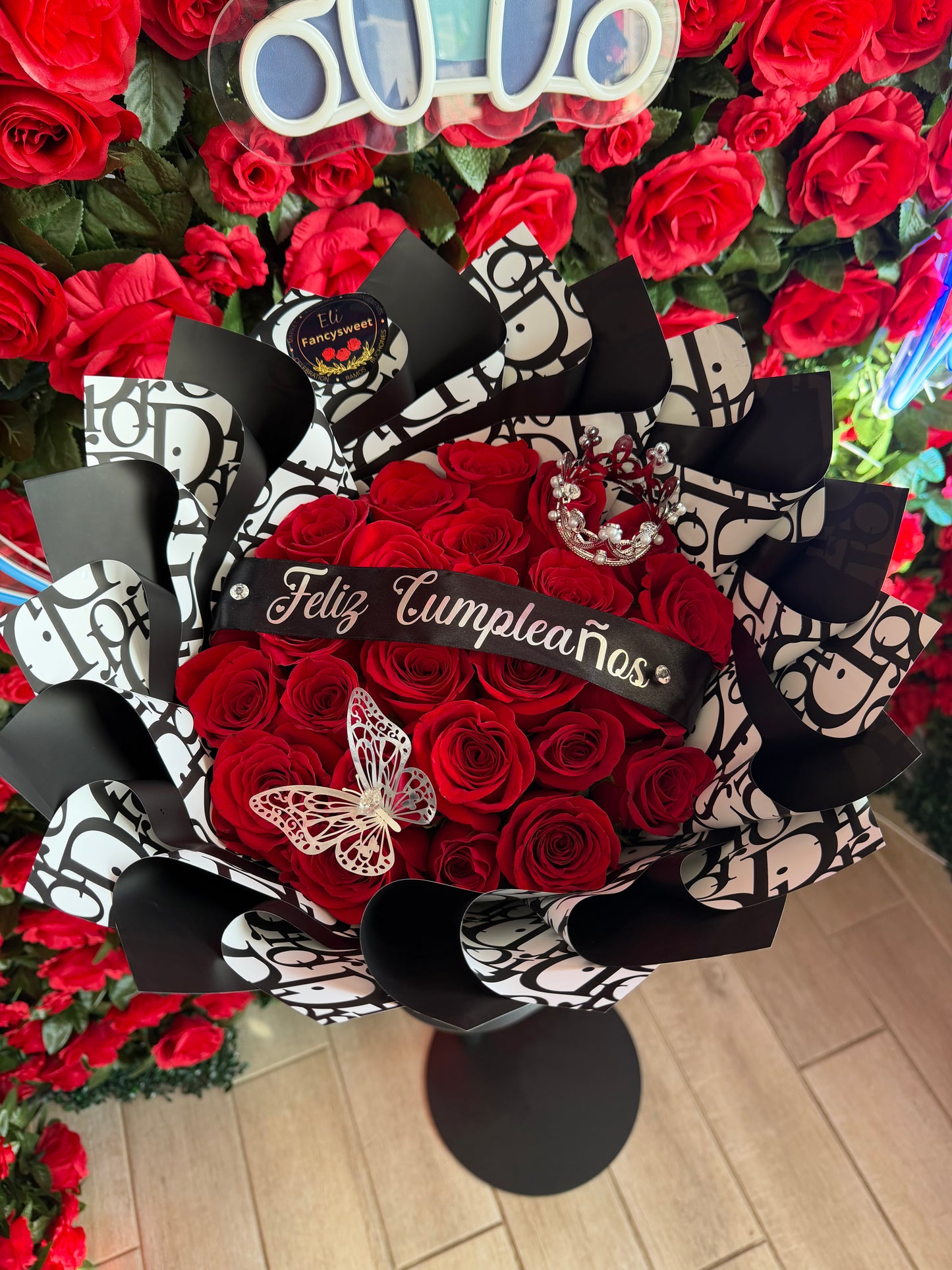 Ramo de 24 rosas rojas con papel negro Dior , una frase personalizado (Feliz cumpleaños ),una mariposa y una mini corona