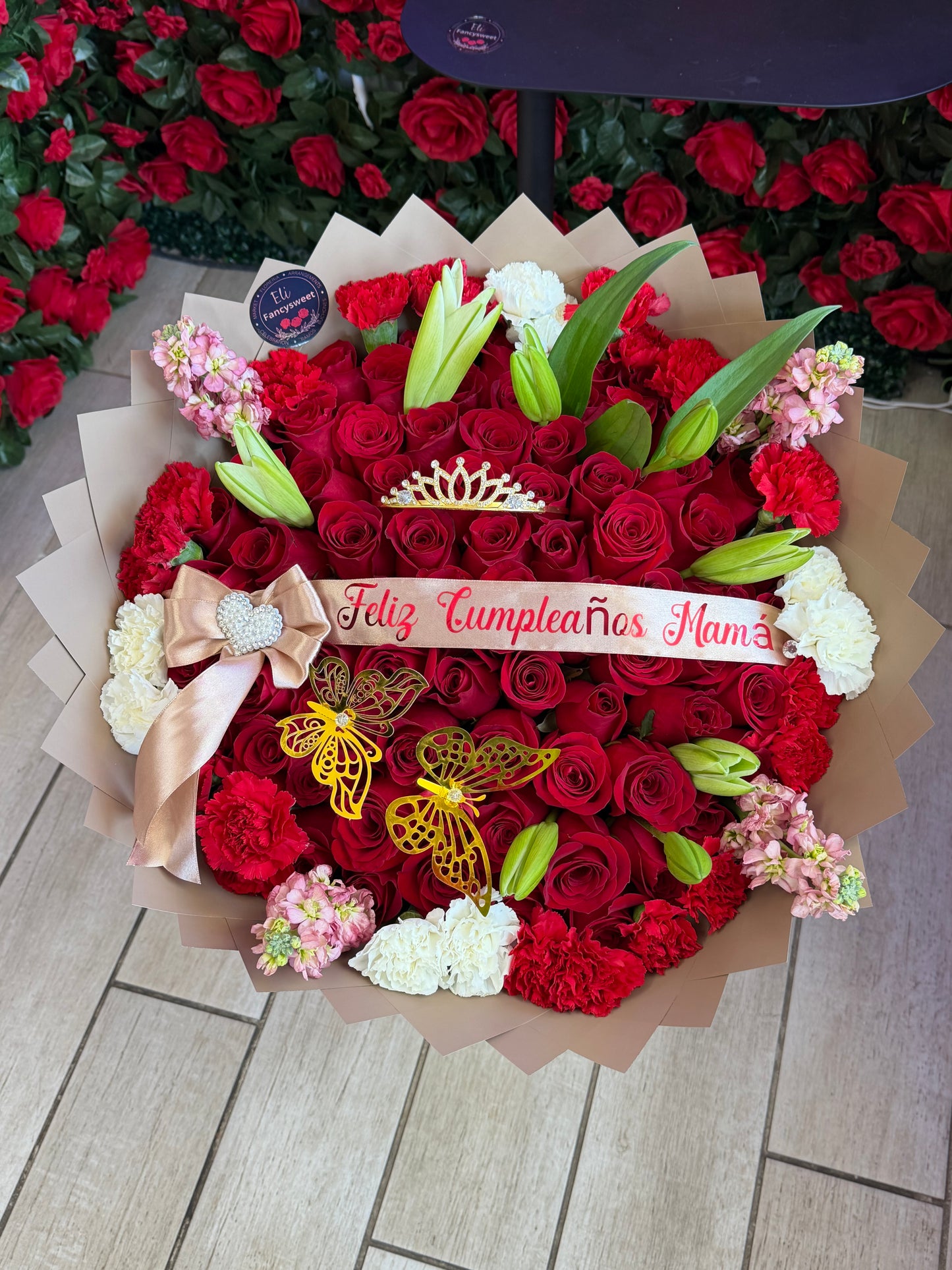 Ramo de 75 rosas rojas  de 50 cm de largo con claveles rojos  alrededor y flores stock alrededor con papel café alrededor con Lilis y una frase personalizada en medio (feliz cumpleaños mamá )