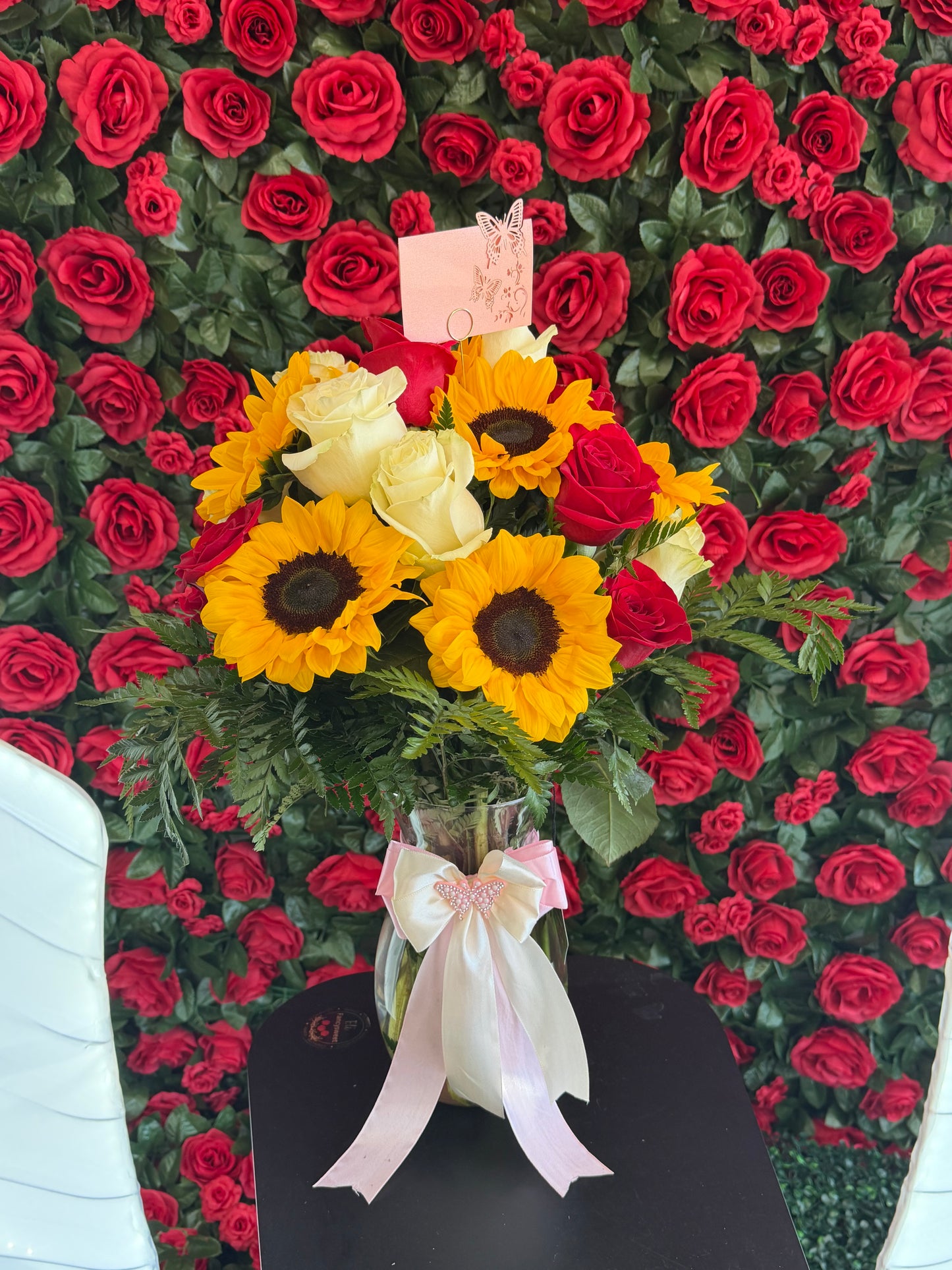 Arreglo floral en florero de cristal , 10 girasoles ,6 rosas blancas , 9 rosas rojas moño color rosado y beige
