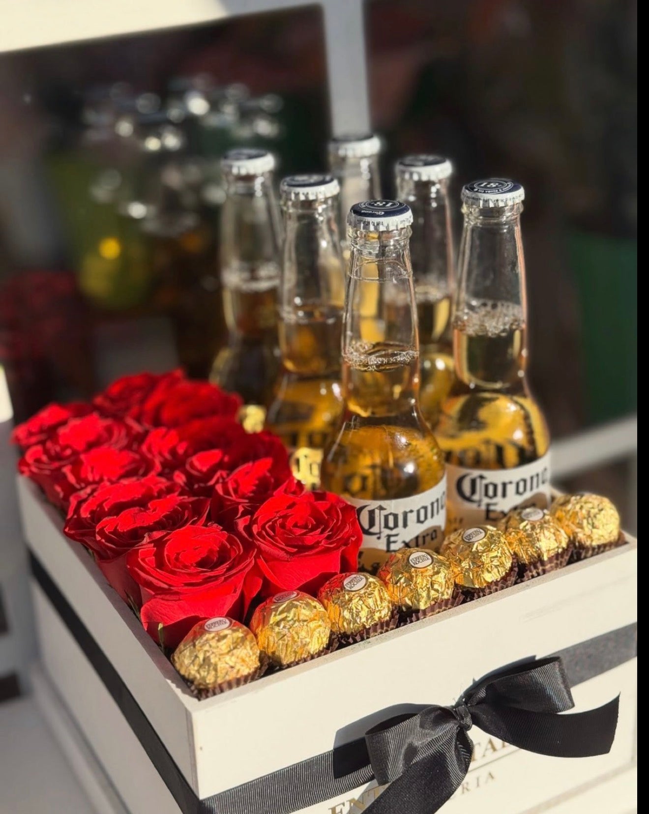 Arreglo de cajita cuadrada , con 12 rosas rojas naturales, 6 cervezas coronas , 7 chocolates Ferrero,