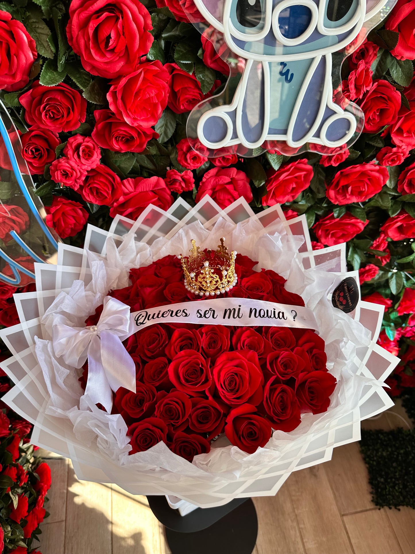 Ramo de 50 rosas rojas con papel blanco transparente , y una capa de papel crepe y una corona mediana y una frase quieres ser mi novia
